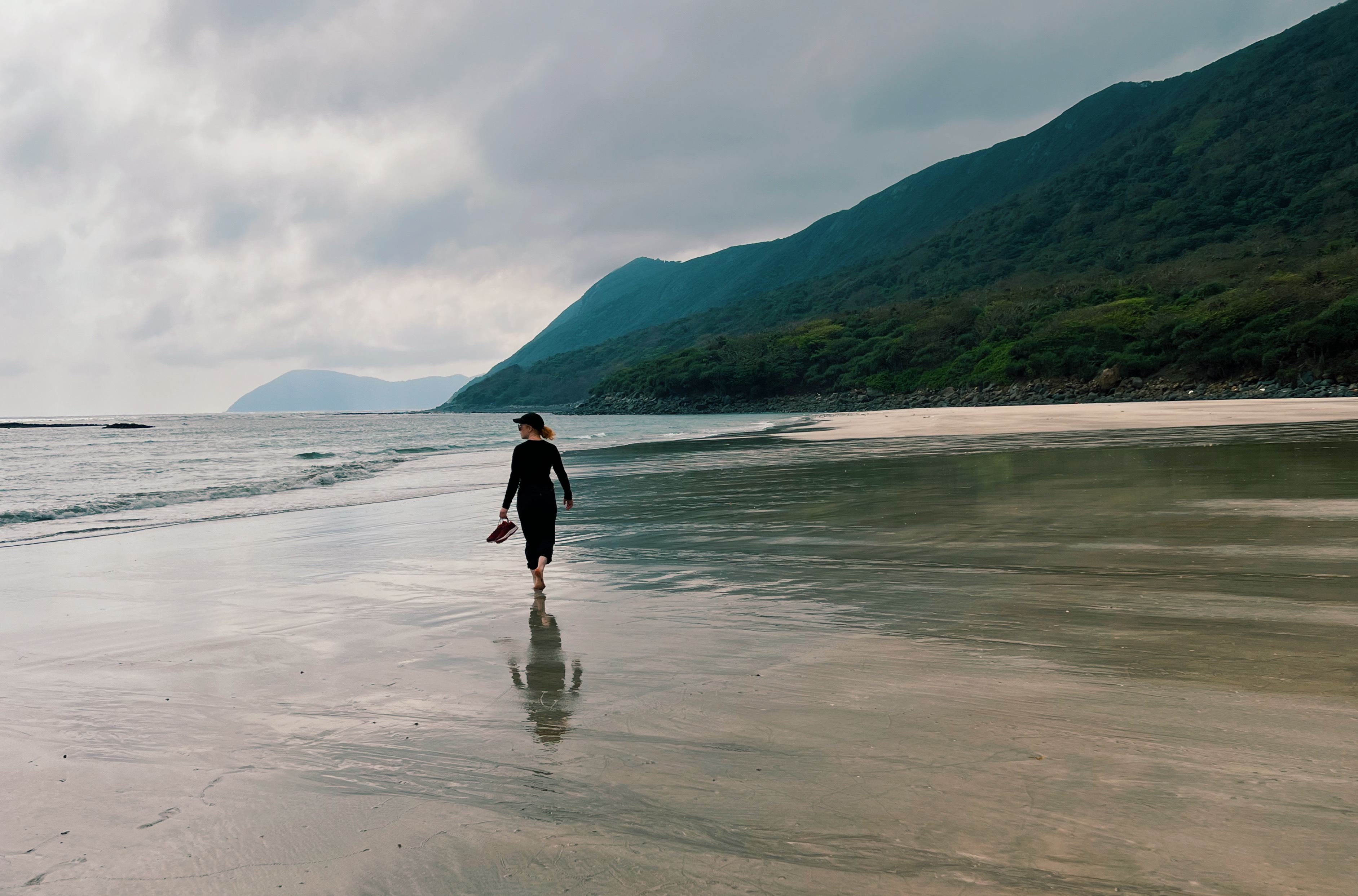 Woman hiking along a long serene beach on Con Dao Island, Vietnam